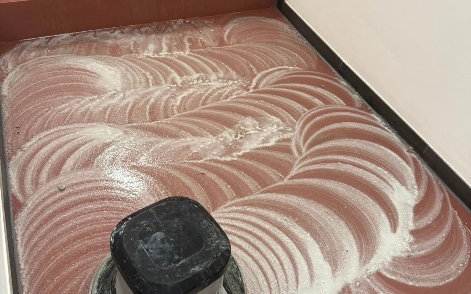 Einscheibenmaschine bei der Grundreinigung eines roten Epoxidbodens im Treppenhaus