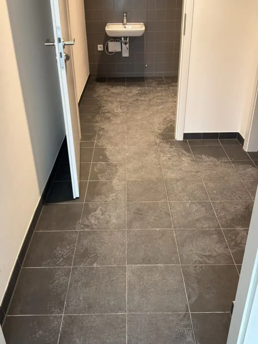 Vorher: Fliesenboden im Neubau-Bad mit Baustaub, Mörtelschleier und Schuhabdrücken